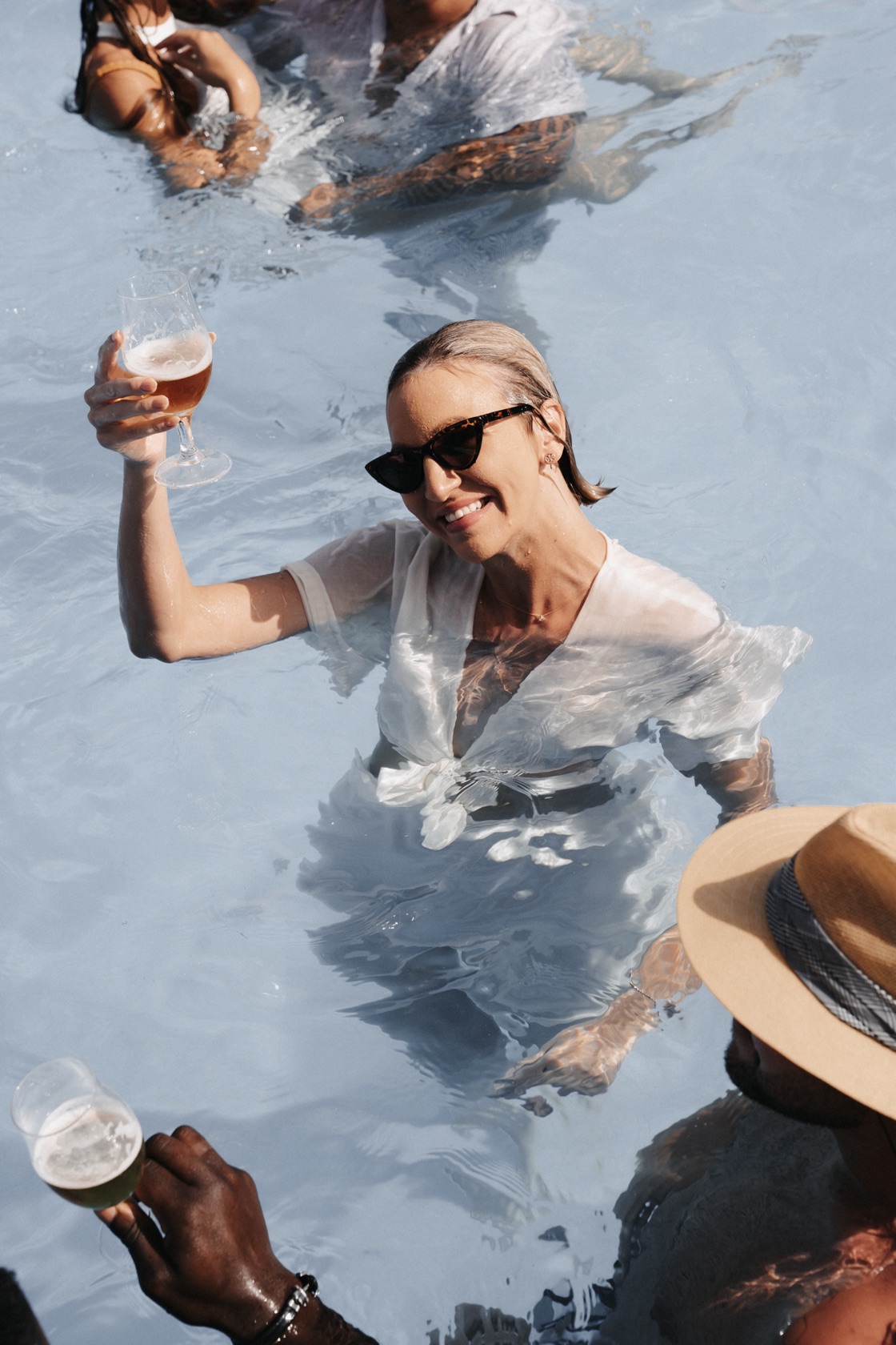Lea Ernst im weißen Kleid im Pool, mit einem Glas in der Hand